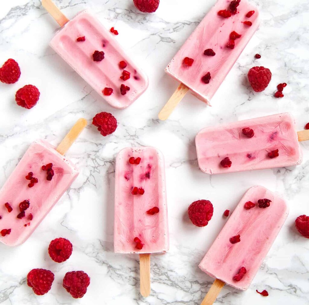 pink-raspberry-popsicles-laying-on-marble-counter 