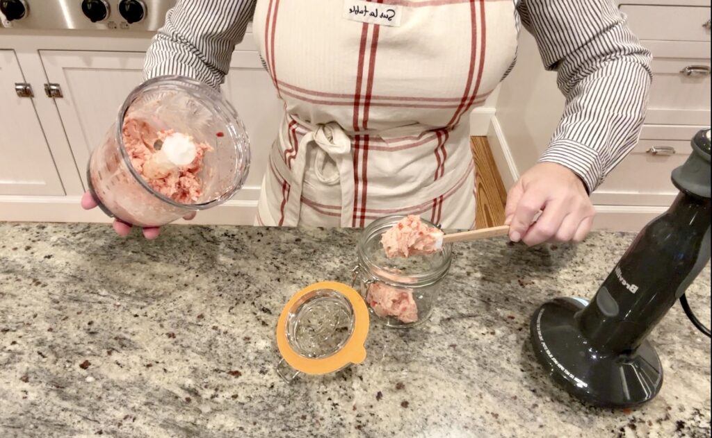 woman putting blood orange butter from breville food processor into kilner clip top jar