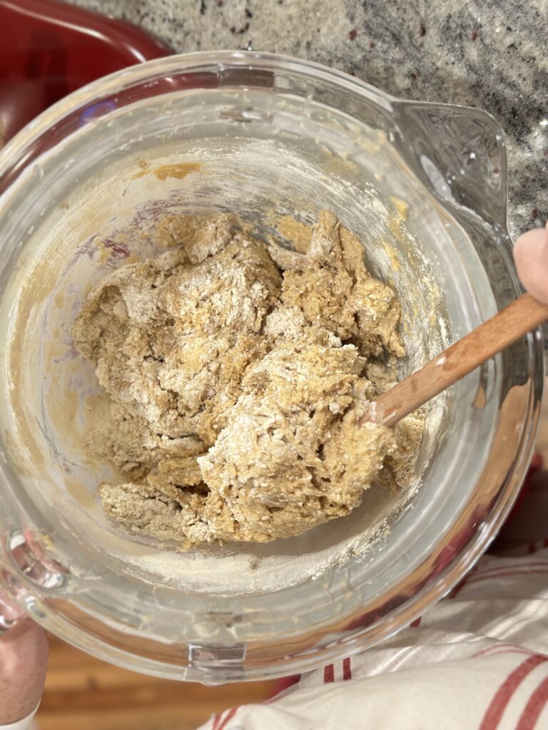 making cookies in a red KitchenAid stand mixer with a glass bowl folding in ingredients