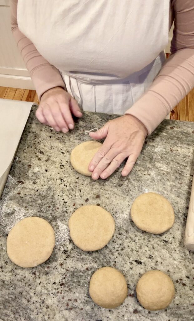 woman in a pink shirt and white apron making whole wheat einkorn pita with Jovial Einkorn flour flattening out dough balls
