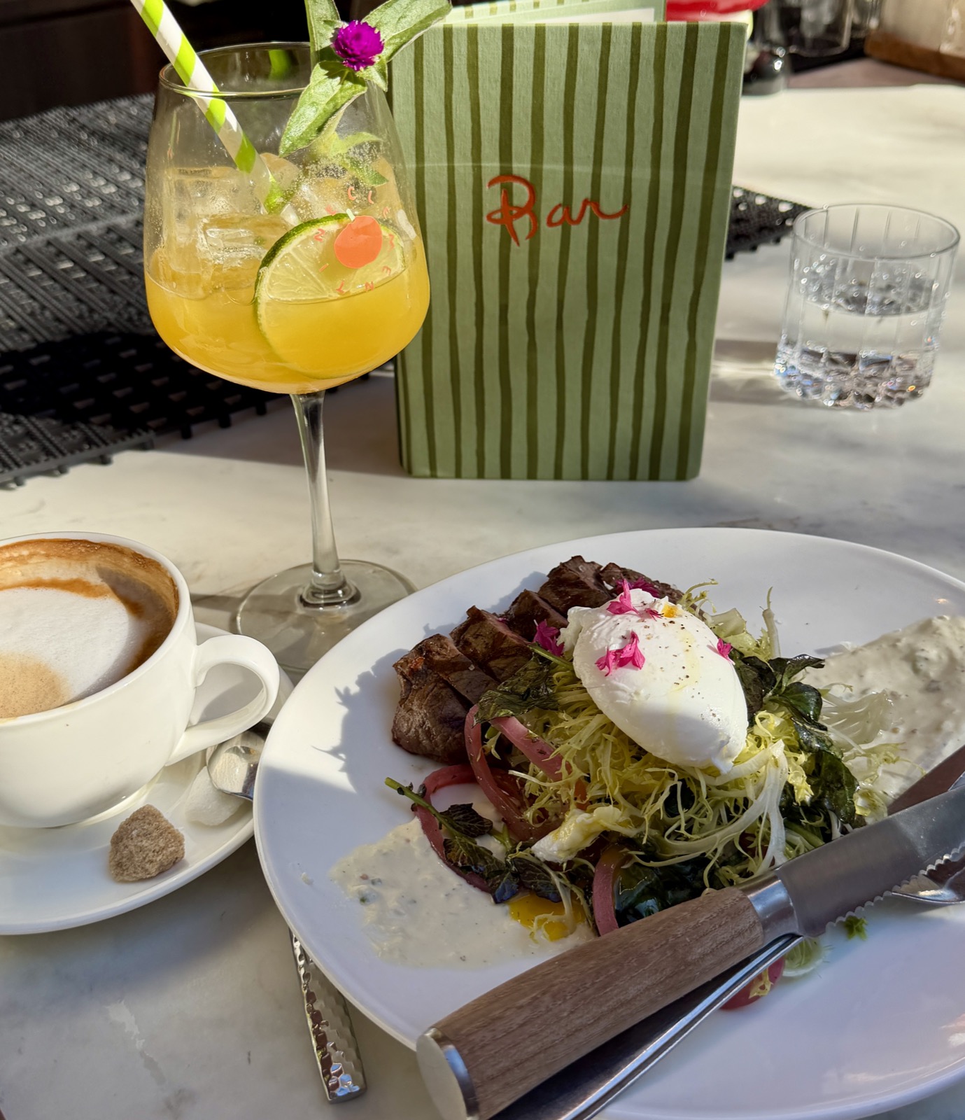 A picture of steak and eggs, a latte, and Clementine Paloma in a stemmed ballon glass from Clementine restaurant in Yountville