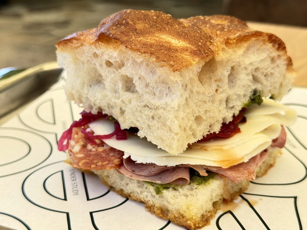 A picture of the Sicilian sandwich from Under-Study in St Helena, CA, with mortadella salami, provolone, marinated peppers, and pickled onions.