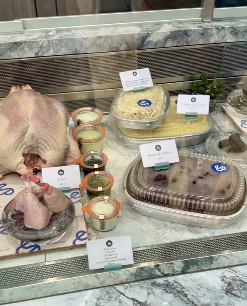 Understudy Saint Helena Napa Valley butcher case with a raw turkey and premade sides