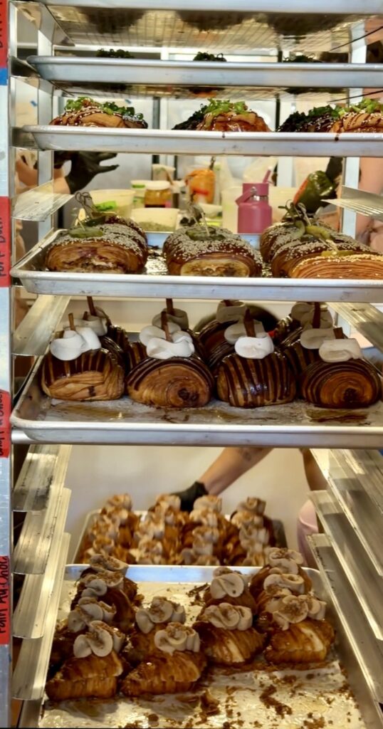 A picture of a filled bun rack at butter and crumble with Mexican hot chocolate croissants, Biscoff, croissant, and chopped cheese pain suisse, and pork bun bear claws