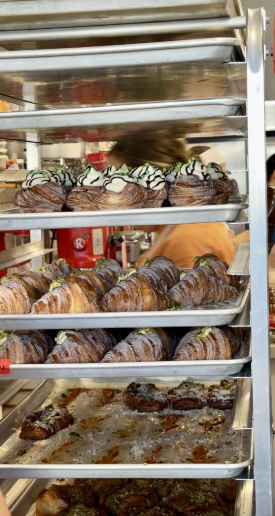 A picture of a bun rack at butter and crumble filled with Guinness cruffins, and pistachio, cardamom sugar croissants