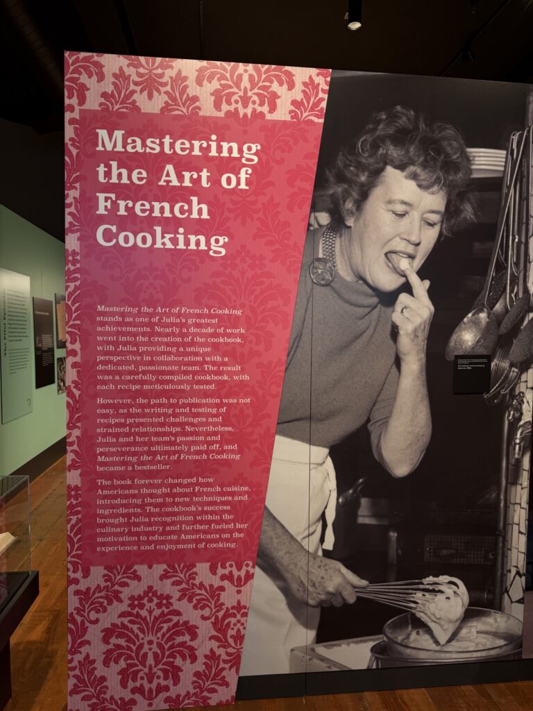 A picture from the Julia Child: A Recipe for Life exhibit, Julia whisking and checking how it tastes
