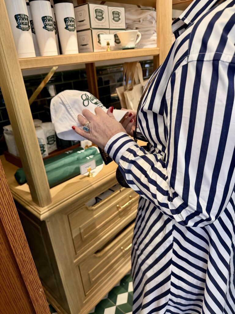 A picture of a woman wearing a blue and white striped Ralph Lauren dress looking at a Ralphs coffee, white and green hat