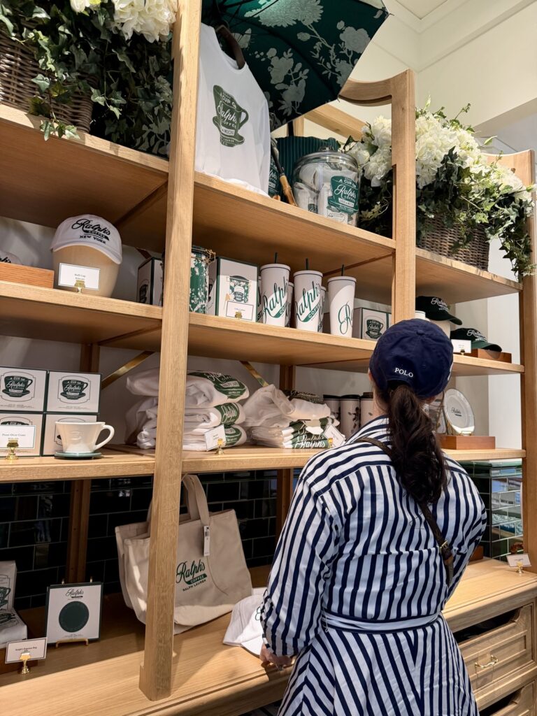 A picture of a woman wearing a blue and white striped Ralph Lauren dress in a blue Ralph Lauren Polo hat looking at Ralph's coffee merch