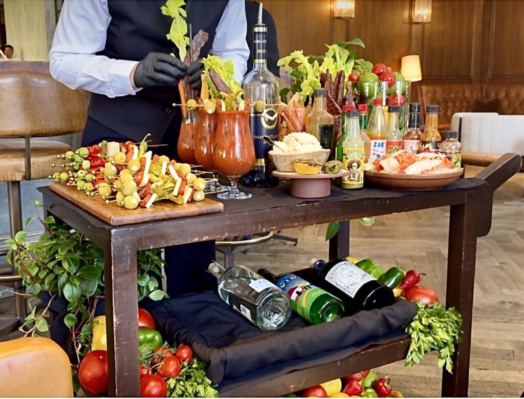 A picture of the bloody Mary kart at Baltaire, finishing making the bloody Mary's, adding bacon, a carrot and celery