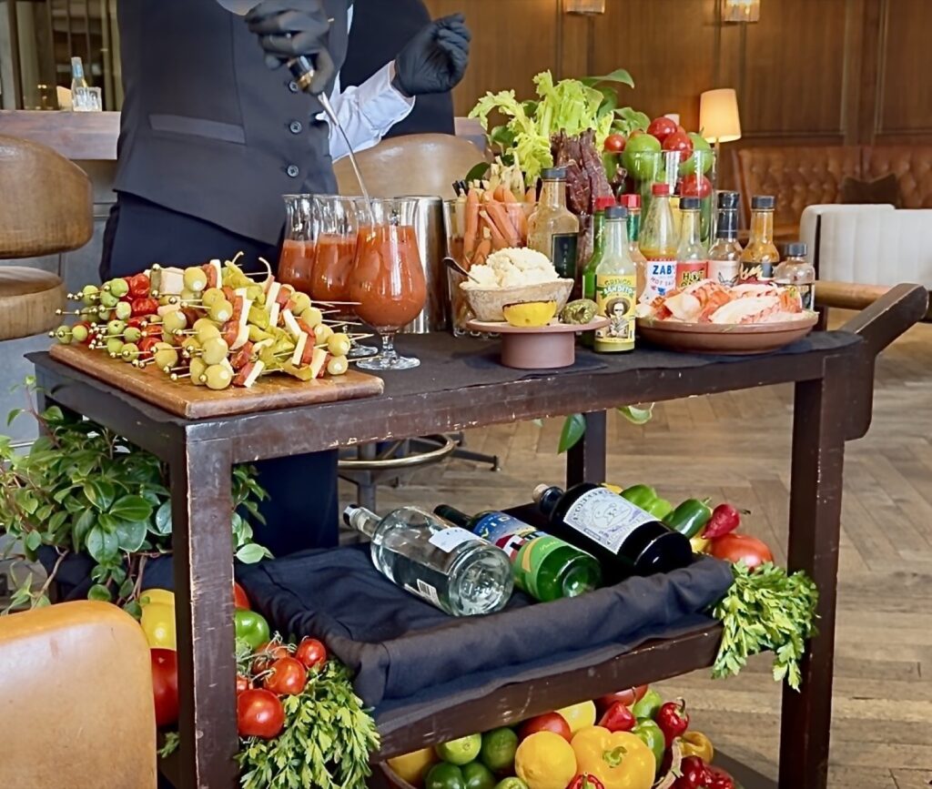 A picture of the bloody Mary cart at Baltaire making a Bloody Mary, adding the vodka looking at a stack of the skewers