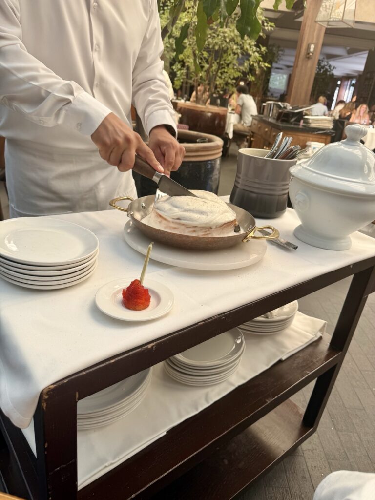 Brunch at Baltaire, a picture of the waiter cutting the cinnamon roll table side