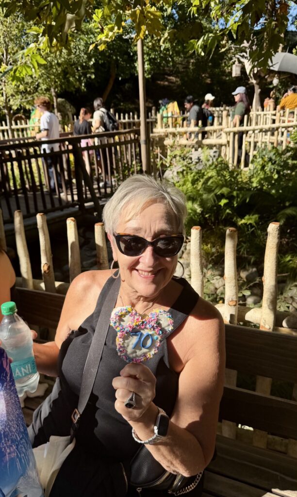 This is a picture of Susan elizabeth from C2P Rachael from A Life Full of Living's mother, holding a Disneyland 70th anniversary treat at Disneyland's Critter Country. The treat was purchased at Pooh's Corner.