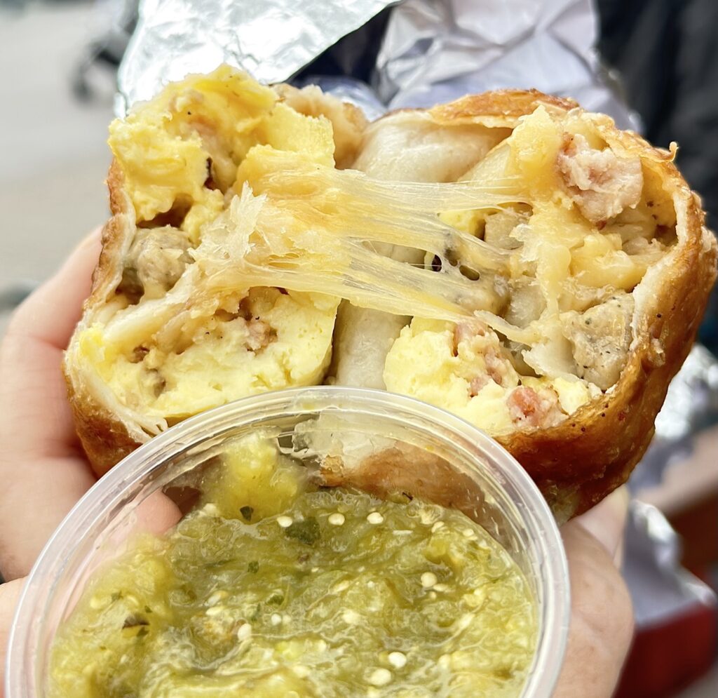 A picture of the breakfast chimichanga from Disneyland, cross-sectioned with green salsa.