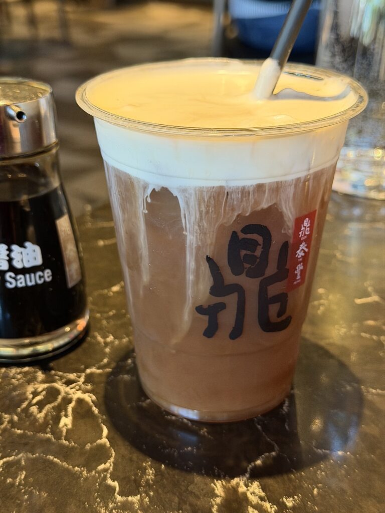 A picture of a to go black iced tea with sea salt cream from Din Tai Fung.