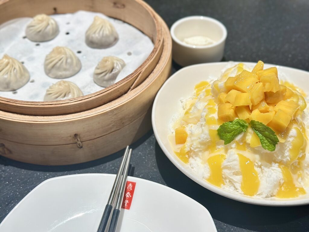A picture of the two desserts from Din Tai Fung, rich chocolate-filled dumplings, served in a bamboo steaming basket with a side of sea salt cream, as well as their other mango ice dessert.