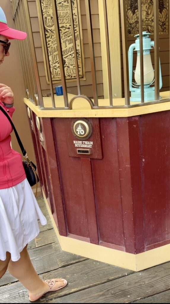 A picture of a woman in a pink Disney Lululemon define jacket and pink Mickey Luluemon hat at Disneyland's 70th Anniversary Magicband Interactive Station in Frontierland.