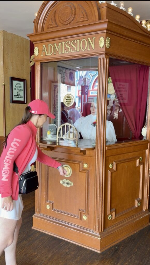A picture of a woman in a pink Disney Lululemon define jacket and pink Mickey Luluemon hat at Disneyland's 70th Anniversary Magicband Interactive Station on Main Street.