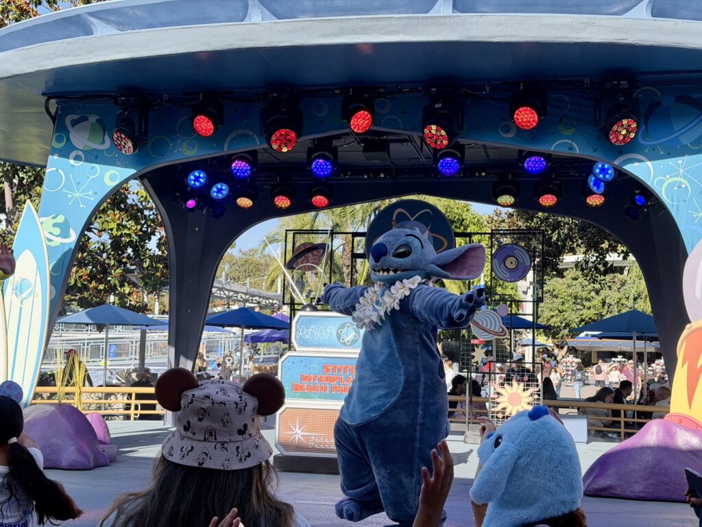 A picture of Disneyland's 70th Anniversary Stitch's Interplanetary Beach Party with Stitch's arms out.